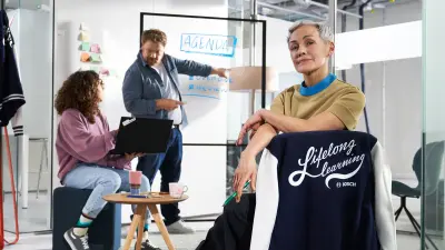 Un asociado posa delante de una estantería de exhibición, llena de gorras impresas con textos de Bosch como Work #LikeABosch.